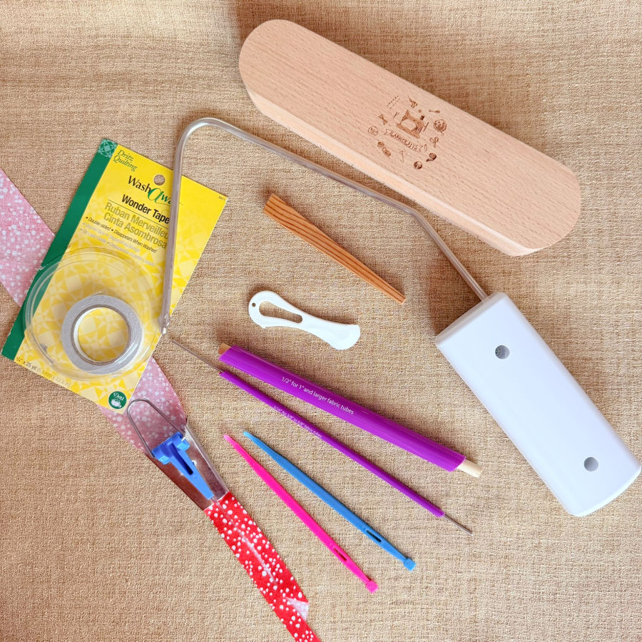 acollection of various sewing tools tape, bodkin, pencil, knee lift, finger presser, hera marker, bias tape maker