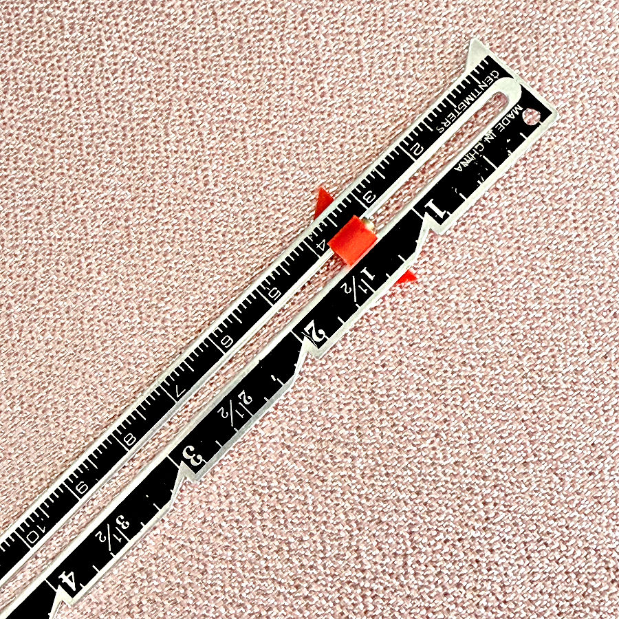 close up of a seam gauge tool with various markings visible
