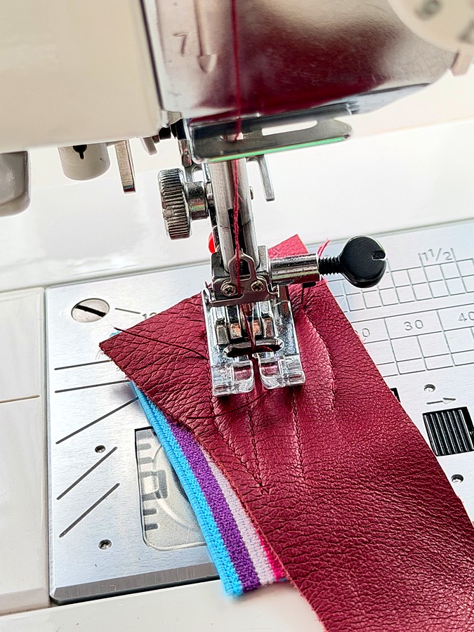 a sewing machine sewing a stitch on a piece of brown leather