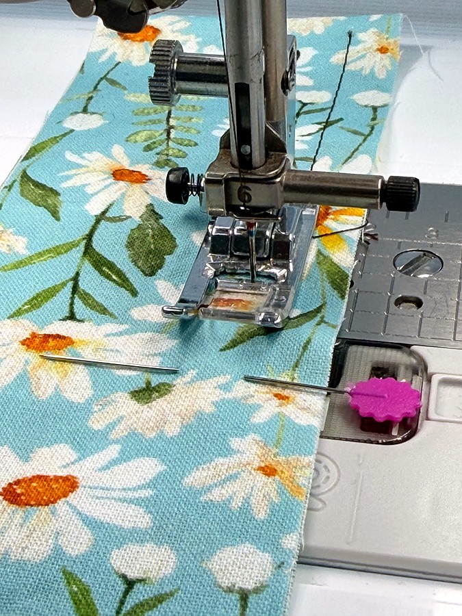 close-up of a sewing machine needle very close to a pin which is in front of it