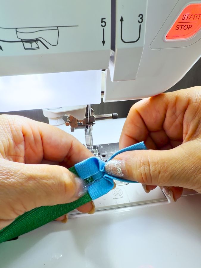a woman holds the fabric and folds it in position over the zipper
