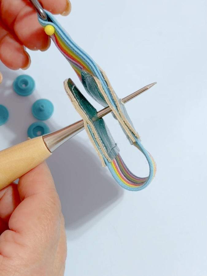 a woman punches with the awl through the leather ends