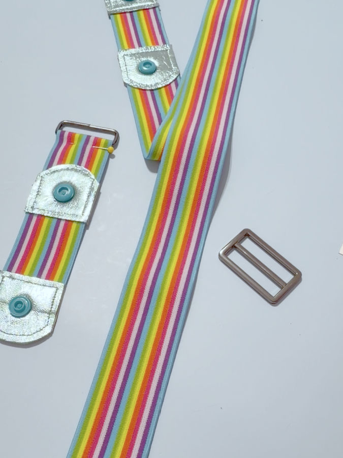 the left side of the image shows the shorter piece of the elastic with the rectangular piece of buckle pinned in place the right side the longer piece of the elastic with the adjuster part not yet mounted