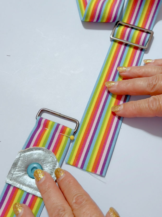 a woman holds the two pieces of the elastic one with the adjuster the other with the loop