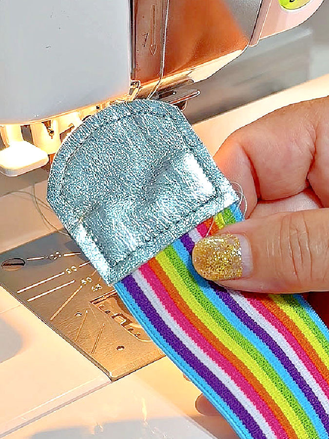 a womans hand holding the finished end piece of leather with stitches visible