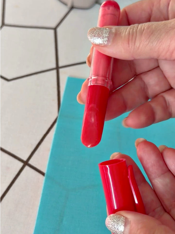 a woman holds a chalk wheel pen in her hand