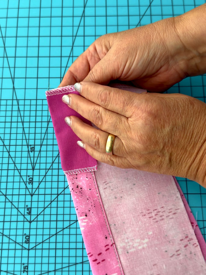 a womans hands shown while folding the insert piece over the hem of the finished piece