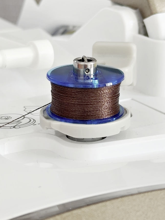 close-up of an almost full bobbin which is inserted in the winding mechanism of a sewing machine
