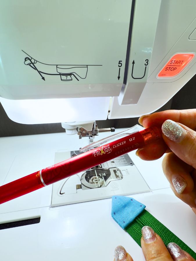 a woman holds a frixion pen near a sewing machine