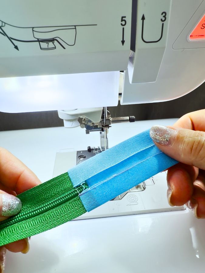 a woman holds the fabric rectangle and the zipper after pressing