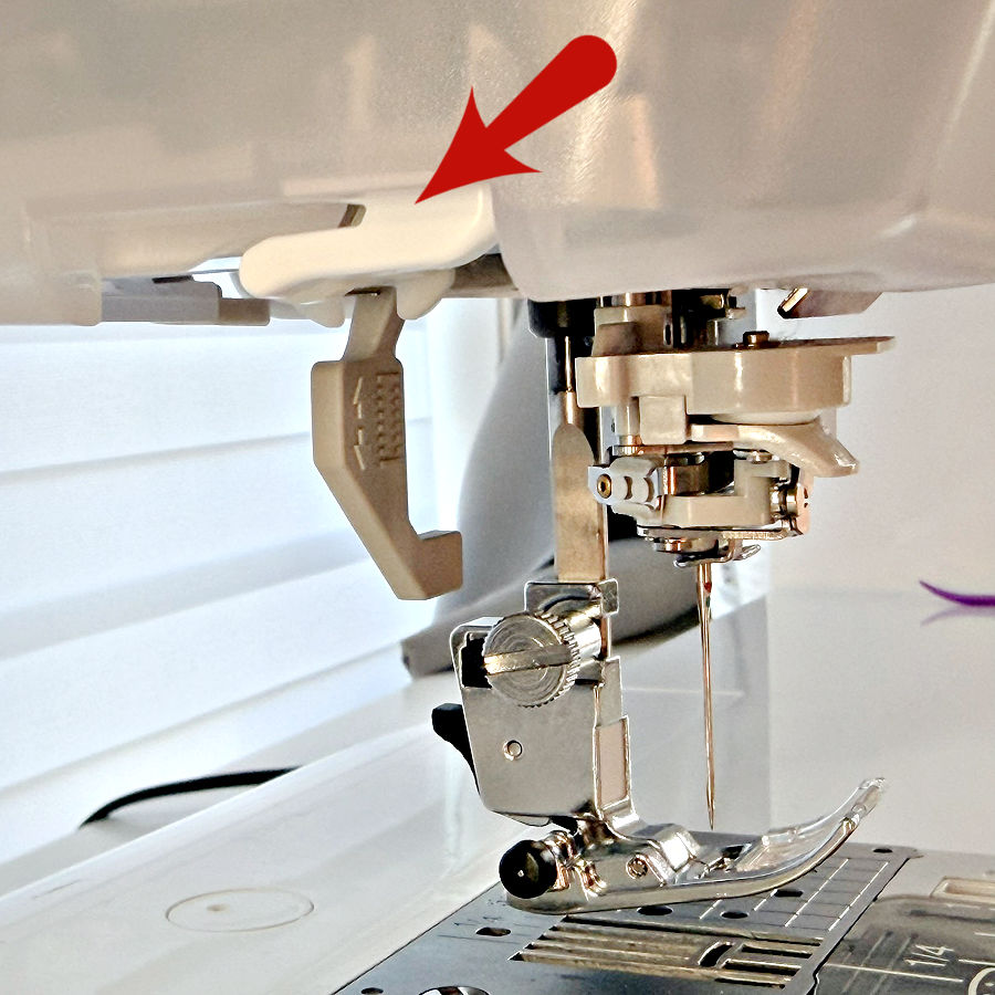 the needle assembly of a sewing machine an arrow points to the thread cutter