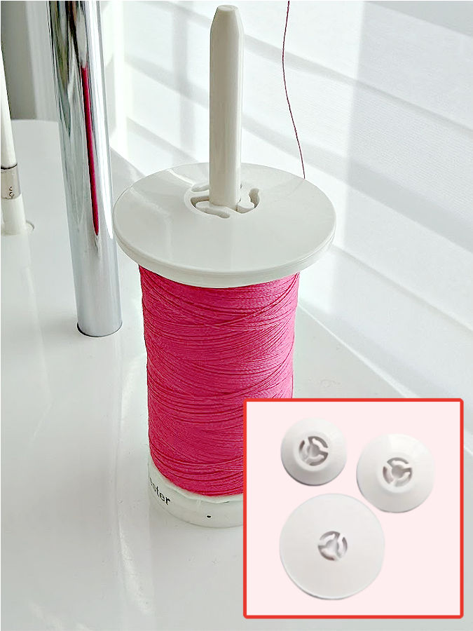 a spool of thread mounted on a vertical pin with a spool cap on top the lower right corner shows three more spool caps of various sizes