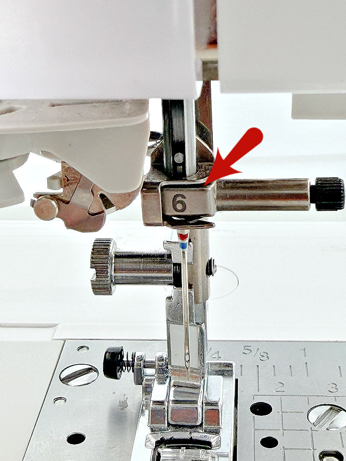 the needle assembly of a sewing machine an arrow points to a small thread guide marked with the number 6