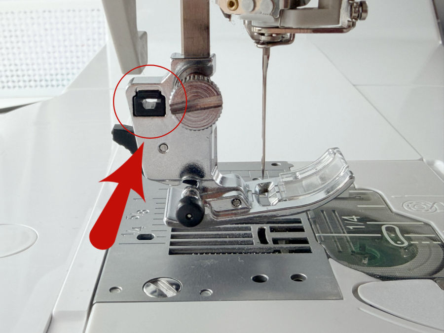 a closeup image of the sewing machine foot assembly an arrow points to an opening in the mechanism
