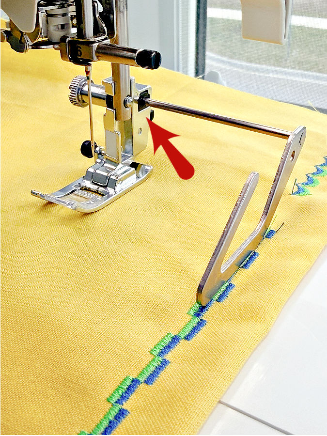 a close up image of a quilting bar mounted on the sewing machine an arrow points to the mounting place