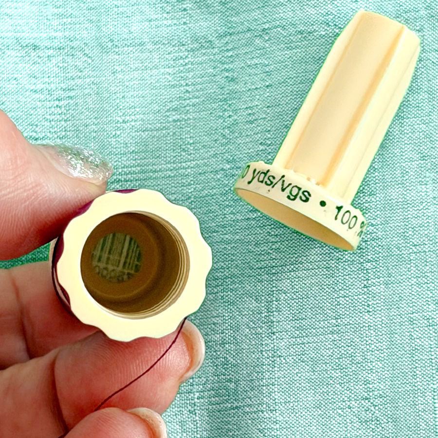 a womans hand holding a thread spool part that looks like a flower another part also visible in the image