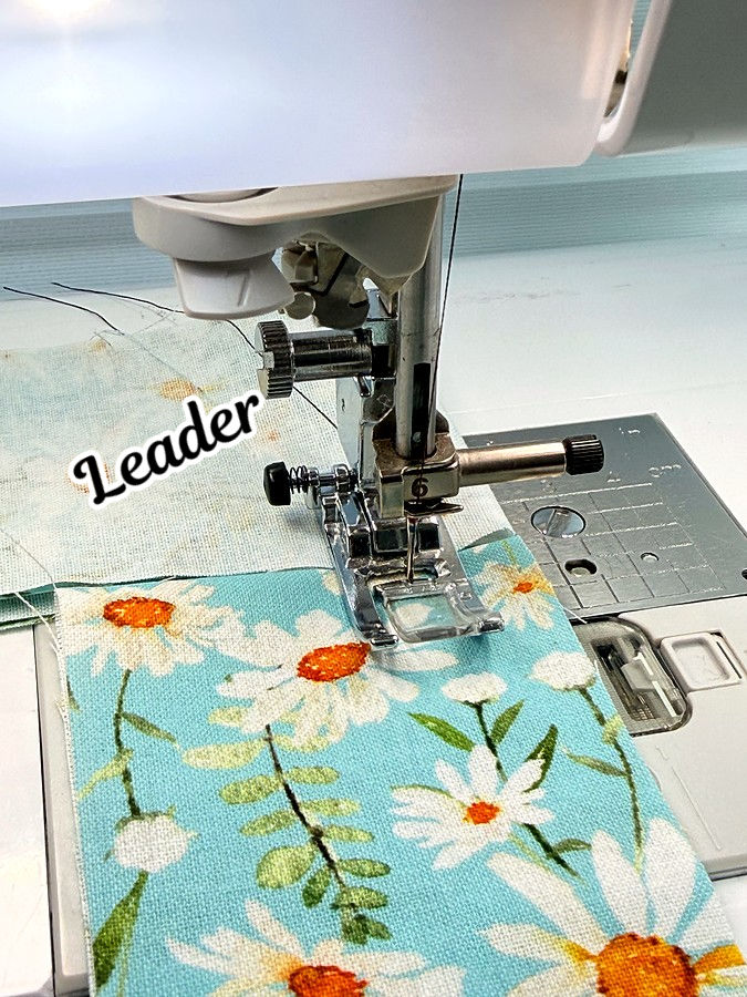 a piece of fabric is behind the presser foot at the beginning of sewing the word leader marked on it