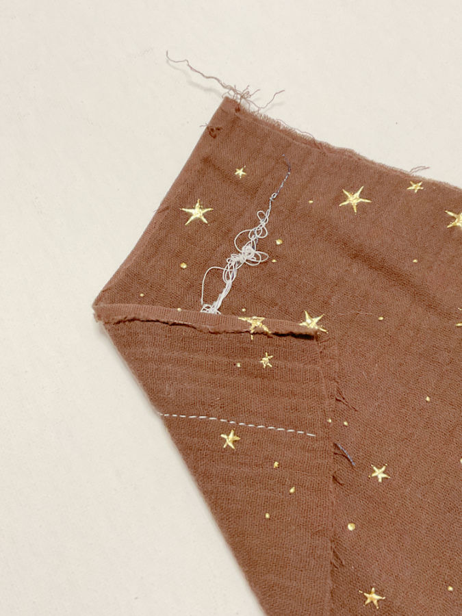 a piece of fabric with a seam folded in half so the underside of the seam is visible with thread loops