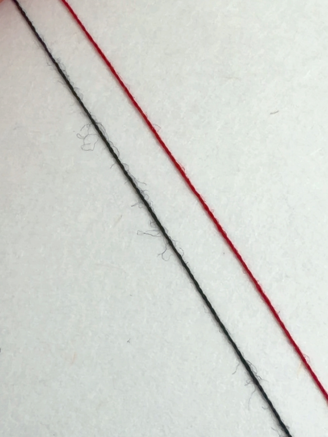 closeup of two strands of thread one obviously fuzzier than the other