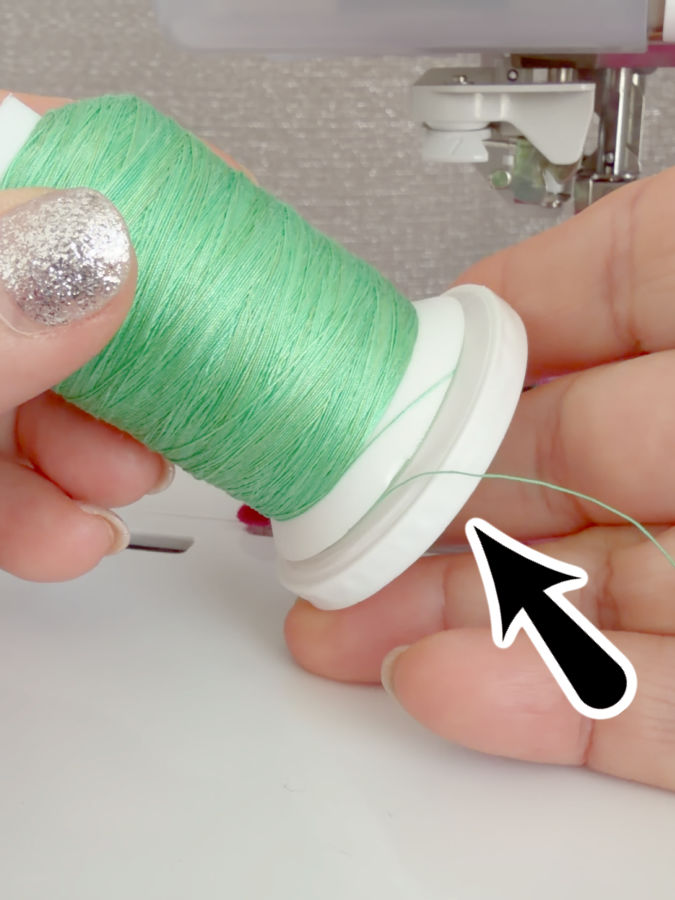 a woman holds a spool of thread with a gap open at the bottom