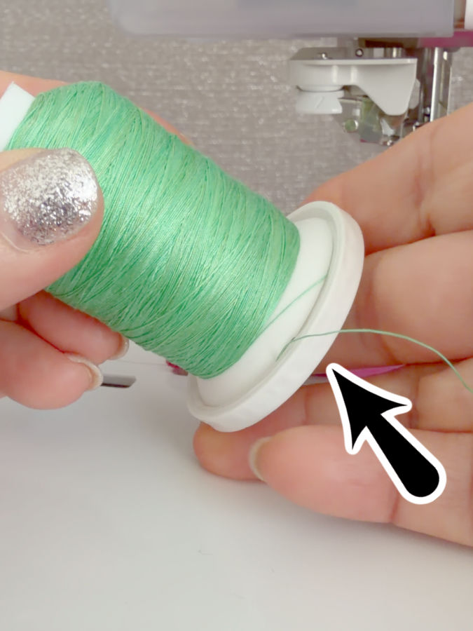 a woman holds a spool of thread with the bottom gap closed