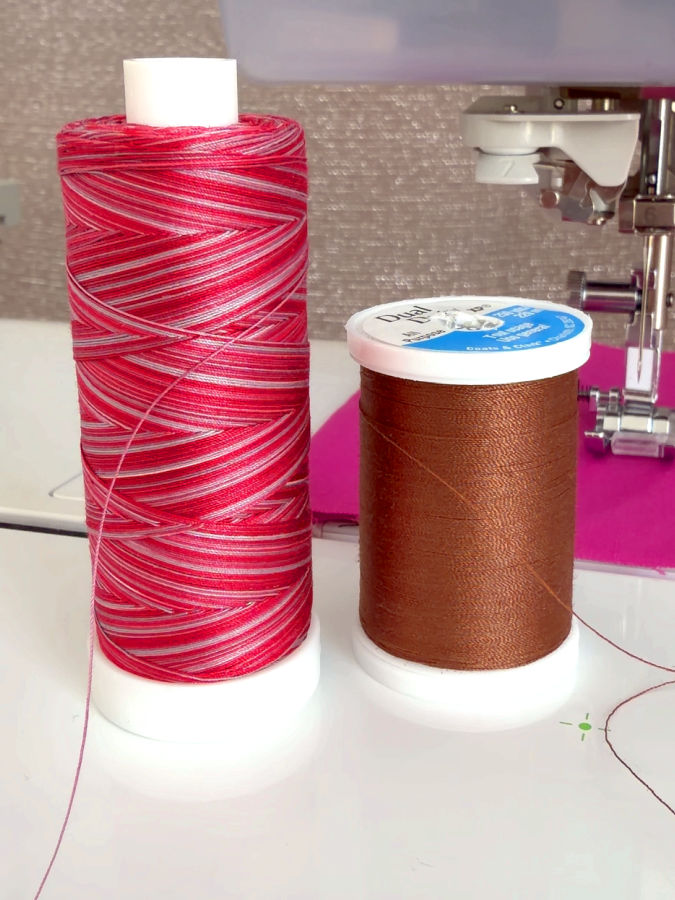 one parallel wound spool and one cross wound spool shown side by side a sewing machine needle assembly in the background