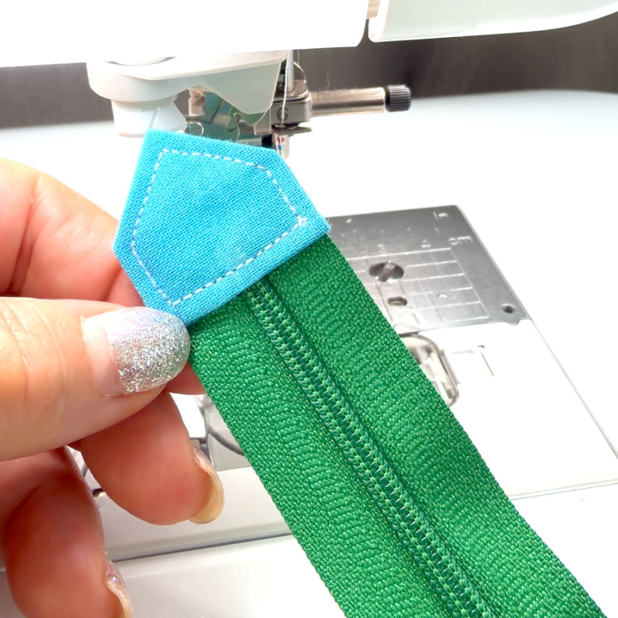 a woman holds in her hand a zipper with an end tab having contrasting colors