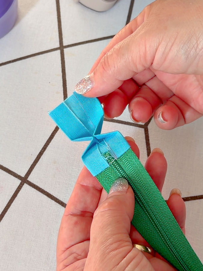 a woman holds the folded fabric which already begins to look like the finished tab